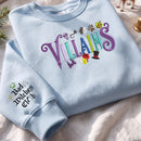 Light blue embroidered sweatshirt featuring colorful Villains typography with movie villain icons and Bad Witches Club sleeve detail
