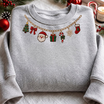 Grey embroidered sweatshirt featuring a gold chain Christmas charm necklace around the neckline with Santa Claus, Christmas tree, gift box, candy cane, red bow, snowflake, and stocking charms.