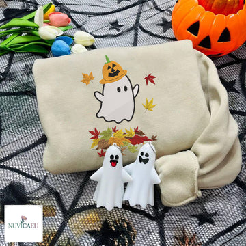 Beige embroidered sweatshirt featuring a cute white ghost wearing a pumpkin hat surrounded by colorful fall leaves.