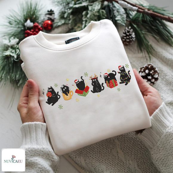 Embroidered off-white sweatshirt featuring a row of six cute black cats in festive Christmas themes with Santa hats, holiday lights, and gifts.