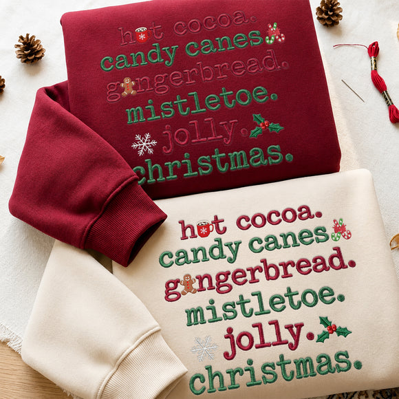 Cream embroidered sweatshirt featuring colorful Christmas text hot cocoa, candy canes, gingerbread, mistletoe, jolly, and christmas with holiday icons