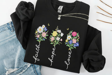 black sweatshirt with floral designs and text 'Faith', 'Hope', 'Love' on a white background.