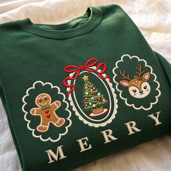 A folded dark green crewneck sweatshirt with embroidered holiday graphics, including a gingerbread man, a Christmas tree, a deer, and the word 'MERRY' in cream letters, laid on a soft white fabric background.