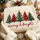 Cream-colored embroidered sweatshirt displaying five snow-dusted Christmas trees with red cursive text reading Merry & Bright.