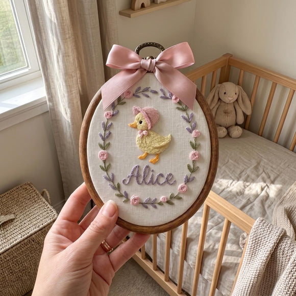 Personalized wooden embroidery hoop with a pink bow, featuring an embroidered rainbow, clouds, hearts, and the name 'Elara Fern' on a white fabric background, styled in a nursery setting.