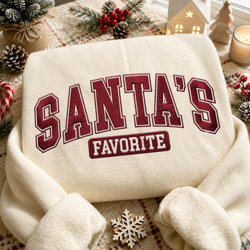Cream embroidered sweatshirt with red varsity text reading Santa's Favorite in high quality stitching on festive Christmas background