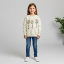 Beige sweatshirt with floral designs and text 'faith', 'hope', 'love' on a wooden surface.
